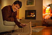 Portrait smiling man reading newspaper in living room