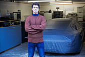 Man standing in front of covered car in garage