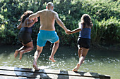Playful family jumping into river