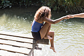 Girl sitting at the edge of riverside dock