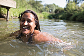 Happy, carefree woman swimming in river