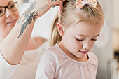 Mother with tattoos fixing daughter's hair