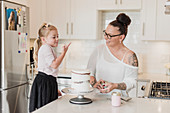 Mother and daughter decorating cake in kitchen
