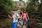 Couple hiking down rocks in woods