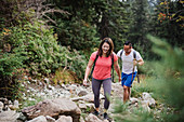 Couple hiking over rocks in woods