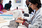 Focused female fashion designer using sewing machine