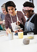 Women shaping clay in art class