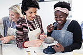Women shaping clay in art class