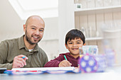 Portrait father and son colouring at table