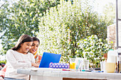 Smiling mother and daughter using laptop at table