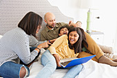 Playful family with laptop on bed