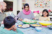 Mother in hijab enjoying dinner with family at table