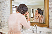 Woman putting earrings on at hotel bathroom mirror