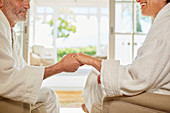 Affectionate couple in spa bathrobes holding hands