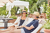 Mature couple reading books at resort poolside