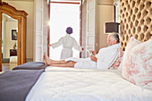 Mature couple in bathrobes relaxing in hotel bedroom