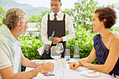 Wine steward showing wine bottle to mature couple