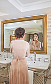 Woman getting ready at hotel bathroom mirror