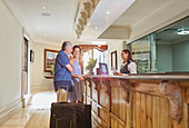 Mature couple with suitcases checking in