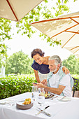 Mature couple with smart phone at patio restaurant