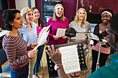 Male conductor leading women's choir singing