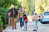 Muslim family watching and riding scooter on sidewalk