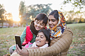 Muslim mother in hijab taking selfie with camera phone