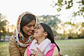 Affectionate, Muslim mother in hijab hugging daughter