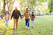 Muslim family holding hands, walking in sunny autumn park