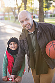 Portrait father and son with basketball in autumn park