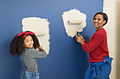 Portrait happy mother and daughter painting wall