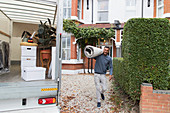 Portrait smiling man carrying rug, moving out of house