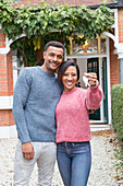 Portrait couple holding house keys outside new house
