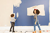 Portrait happy brother and sister painting wall