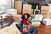 Mother and daughter hugging among boxes