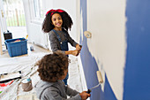 Portrait happy girl painting wall with brother