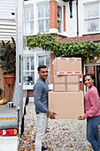 Portrait couple moving house, carrying cardboard boxes