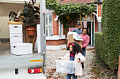 Family moving out of house, loading moving van