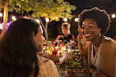 Happy women friends enjoying dinner garden party