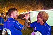 Happy friends cheering, watching soccer match on screen