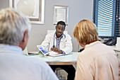 Doctor with digital tablet talking to senior couple