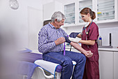 Female nurse checking blood pressure of senior patient