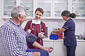 Female nurse checking blood pressure of senior patient