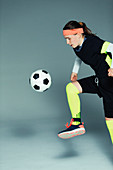 Teenage girl soccer player kicking the ball