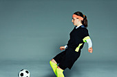 Teenage girl soccer player kicking soccer ball