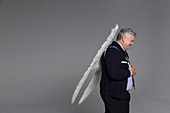 Smiling businessman wearing angel wings