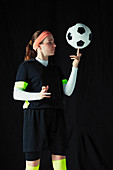 Teenage girl balancing soccer ball on finger