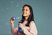 Happy, playful girl with bubble wand blowing bubbles
