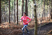 Woman running on trail in autumn woods