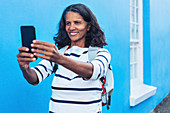Happy female tourist taking selfie with smart phone